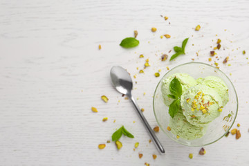 Delicious green ice cream served in dessert bowl on white wooden table, top view. Space for text