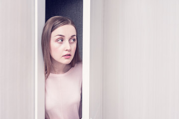 Girl spying on the door, portrait, copy space, toned