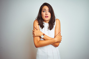 Young beautiful woman wearing dress standing over white isolated background shaking and freezing for winter cold with sad and shock expression on face