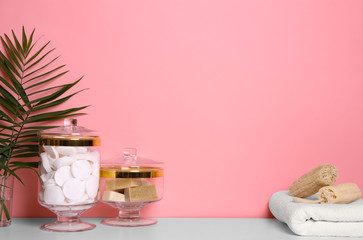 Composition of glass jar with cotton pads on table near pink wall. Space for text