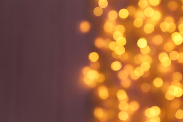 Blurred view of Christmas lights on color background, space for text