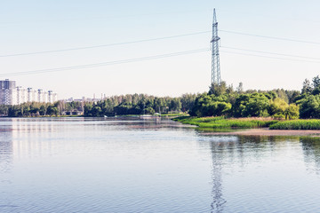 High voltage electric poles in the city of Minsk near Drozdovsky reservoir, Belarus. The high voltage pole, the blue summer sky, toned
