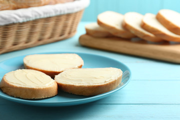 Fototapeta na wymiar Slices of tasty fresh bread with butter on light blue wooden table