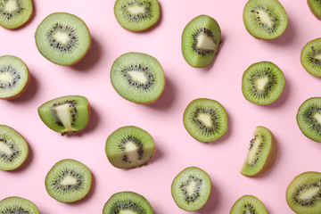 Fototapeta premium Pieces of kiwis on pink background, flat lay