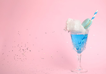 Cocktail with cotton candy in glass on pink background, space for text