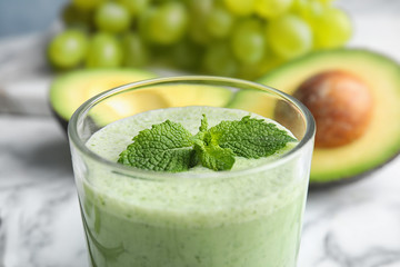Glass of tasty avocado smoothie with mint on table, closeup