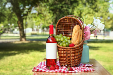 Composition with picnic basket on table outdoors