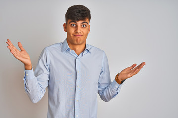 Young indian businessman wearing elegant shirt standing over isolated white background clueless and...
