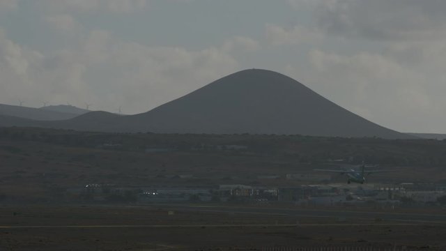 An early moning aircraft taking off - in front of a grey mountain