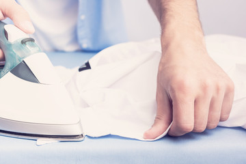 Man ironing clean shirt, men's hands, closeup, toned
