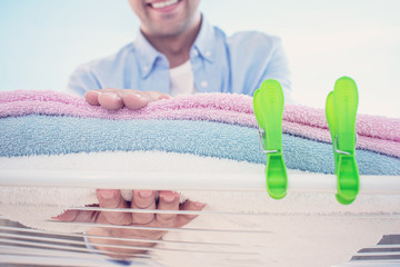 Happy man holds dry towels outside in summer, close up, toned, cropped image. The concept of cleanliness and housework