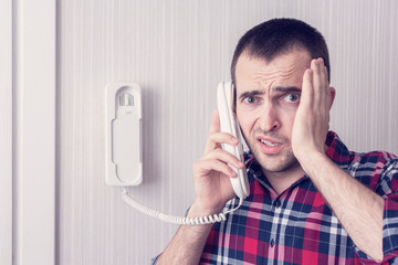Frightened man with intercom or land line phone, person upset, bad news, portrait, toned