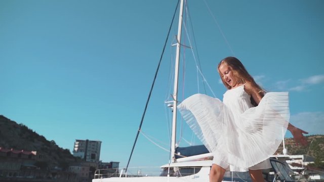Kid girl walking near boat on sea with smile