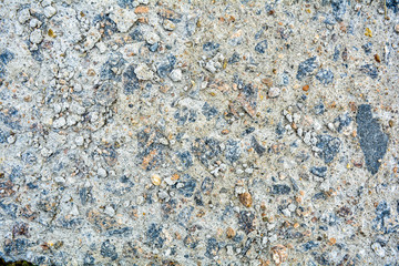 Ground street surface of broken asphalt or cement with pothole and stone pebbles