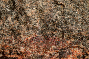Abstract blurred natural background. Black with pink-orange rough surface of granite. Design and construction concept.