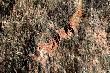 Abstract blurred natural background. Black with pink-orange rough surface of granite. Design and construction concept.