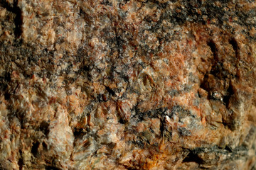 Abstract blurred natural background. Black with pink-orange rough surface of granite. Design and construction concept.