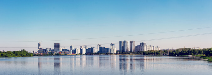 Sunny day in the city, apartment buildings, blue sky with clouds, Komsomol lake, Minsk, copy space, horizontal