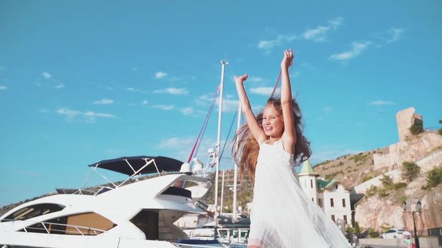 Kid girl running around near water with boat