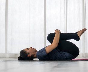 Beautiful asian young woman wearing sportswear practicing yoga in studio,natural light.Concept : yoga poses for beginner.