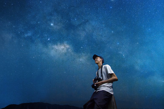 Happy Youth photographer holding a camera while looking to the sky to enjoy a beautiful stars at night