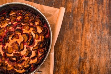 food background. plum pie in metallic cake pan on the wooden table