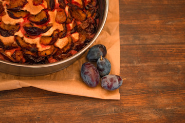 food background. plum pie in metallic cake pan on the with fresh plums wooden table 