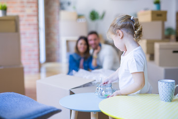 Beautiful family sitting on the floor playing with his kid at new home around cardboard boxes