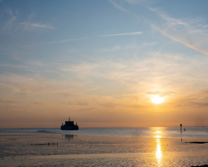 Obraz premium ferry from ameland arrives during sunset at harbor of Holwerd in dutch province of friesland