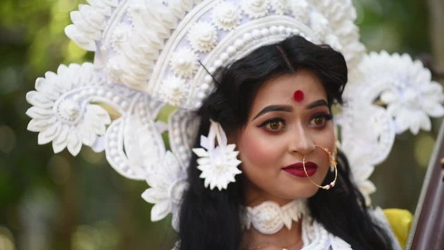 Close up portrait of beautiful Indian girl posing as Hindu Goddess Saraswati, slow motion