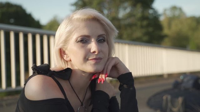 Close-up Cinematic shot of a middle aged blonde lady giving the camera a dreamy sensual look and red nails - slowmotion