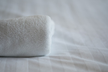 roll white towel on bed in hotel