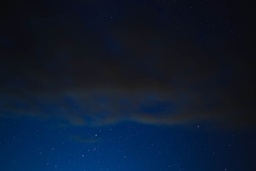 Obraz na płótnie Canvas blue starry sky through gray clouds