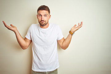 Young handsome man wearing casual white t-shirt over isolated background clueless and confused...