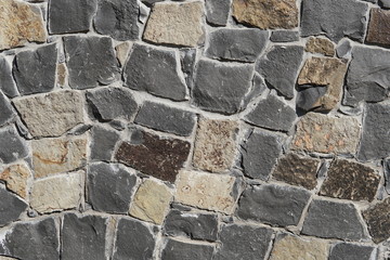 Decorative wall of artificial torn stone in brown tones. Stone masonry in geometric pattern as background or texture.