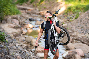 A man with a bicycle on his shoulder crosses the river and holds out his hand.