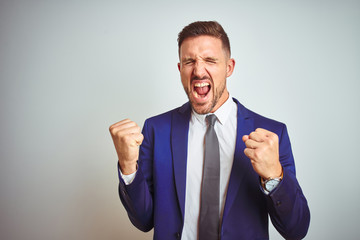 Young handsome business man over white isolated background very happy and excited doing winner gesture with arms raised, smiling and screaming for success. Celebration concept.