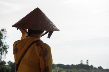 Vietnamese women in flowered shirt with conical hat.