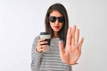 Chinese woman wearing sunglasses drinking take away coffee over isolated white background with open hand doing stop sign with serious and confident expression, defense gesture