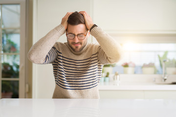 Young handsome man wearing glasses at home suffering from headache desperate and stressed because...