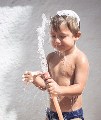 Boy showering with a hose and having fun with the water