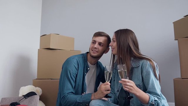 Caucasian happy man and woman discussing design on new house, flat with champagne glasses in the hands.