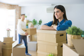 Young couple moving to a new home, beautiful woman smiling leaning on cardboard boxes