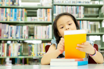 Portrait of Smiling cute Asia little Girl sitting in library at school  looking to a book  , education learning knowledge growth back to school concept