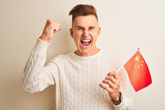 Young handsome man holding Chinese China flag over isolated white background annoyed and frustrated shouting with anger, crazy and yelling with raised hand, anger concept