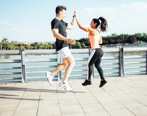 Caucasian man and Latin woman greet each other before they start doing sports on the side of a lake in a park in the city of Madrid