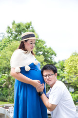 Naklejka na ściany i meble Happy family. Pregnant mother with her husband at the park.