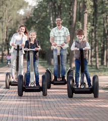 Fototapeta na wymiar happy family riding electric scooters in the Park