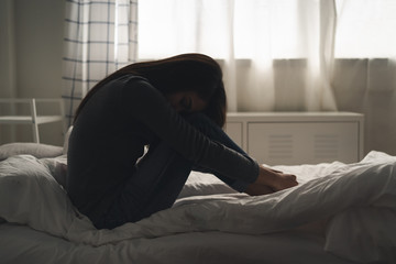 Suffer from depression , mental health problem. asian young woman sitting on the bed feeling...