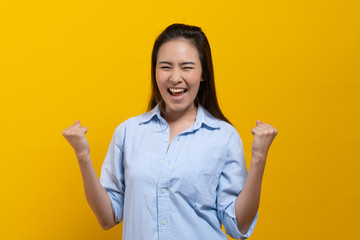 Happy beauty asian young woman showing excite expression.  Shot in studio isolated on yellow background.